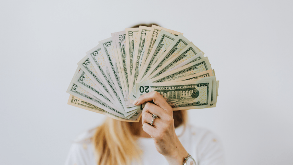 A person covering their face with a fan of money.