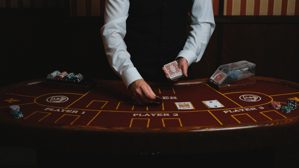 A person in a vest and tie playing cards on a casino table.