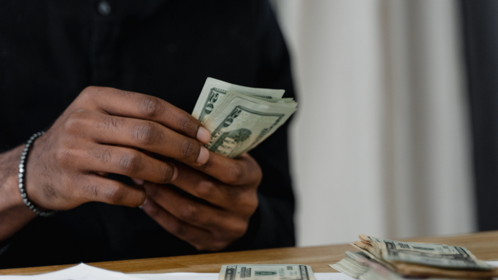 A person is counting money on a table in front of them.