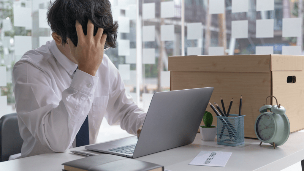 A person sitting at a desk with their head in their hands.