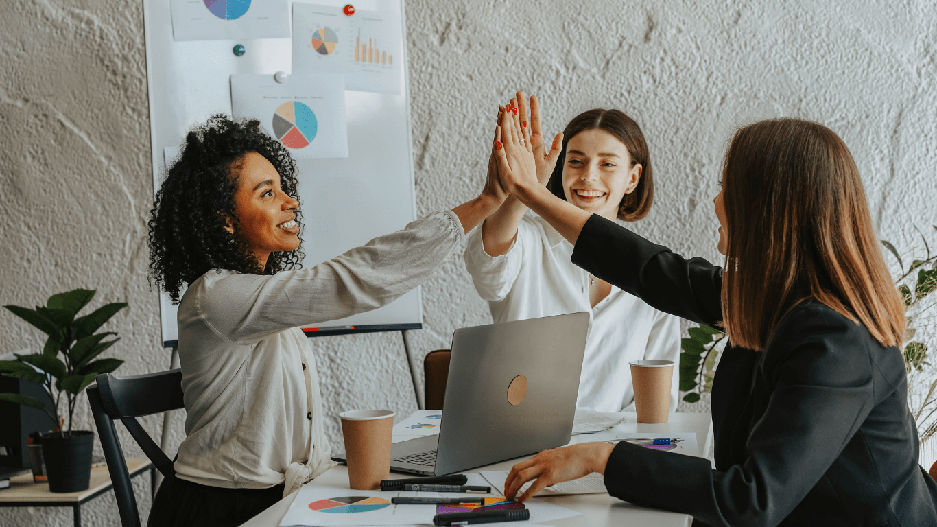 a group of people in an office raising their hands