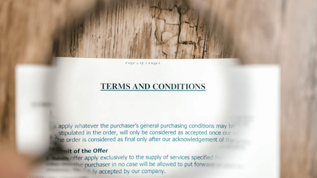 a hand holding a magnifying glass over a document on a wooden table