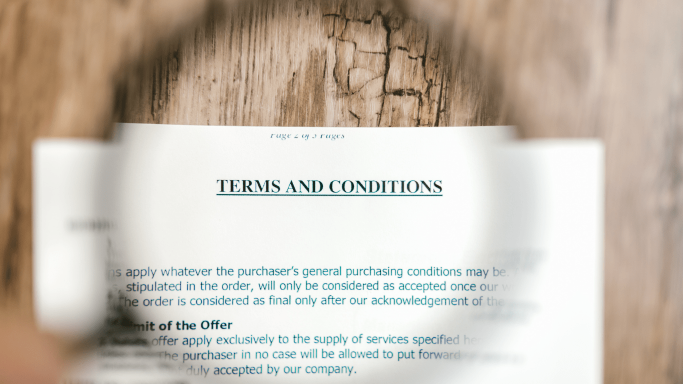a hand holding a magnifying glass over a document on a wooden table
