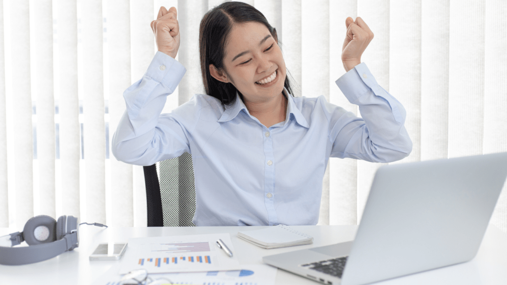 A person is sitting at a desk with their arms up in the air.