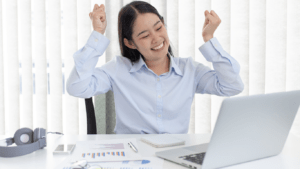 A person is sitting at a desk with their arms up in the air.
