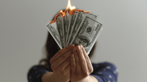 A person holding up a burning money