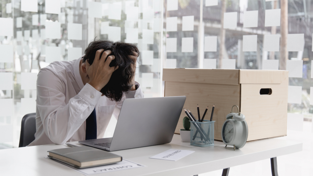 A person sitting at a desk with their head in their hands.