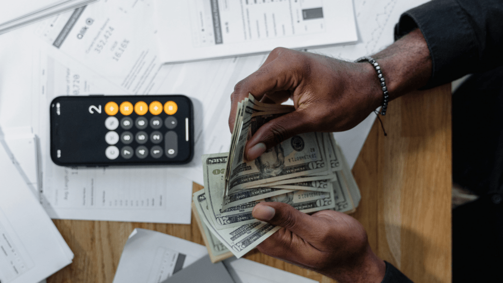 A person is counting money on a table in front of them.