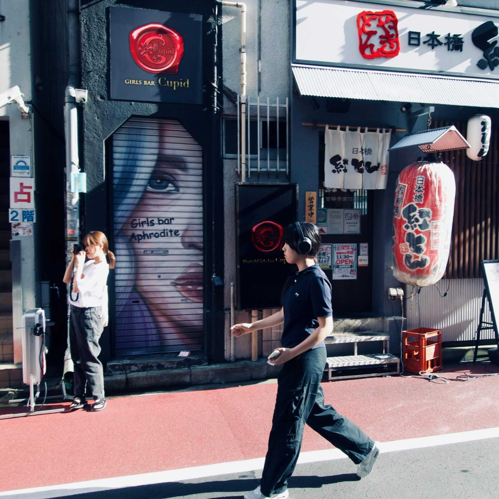 Urban street scene in Japan with pedestrians and colorful murals.